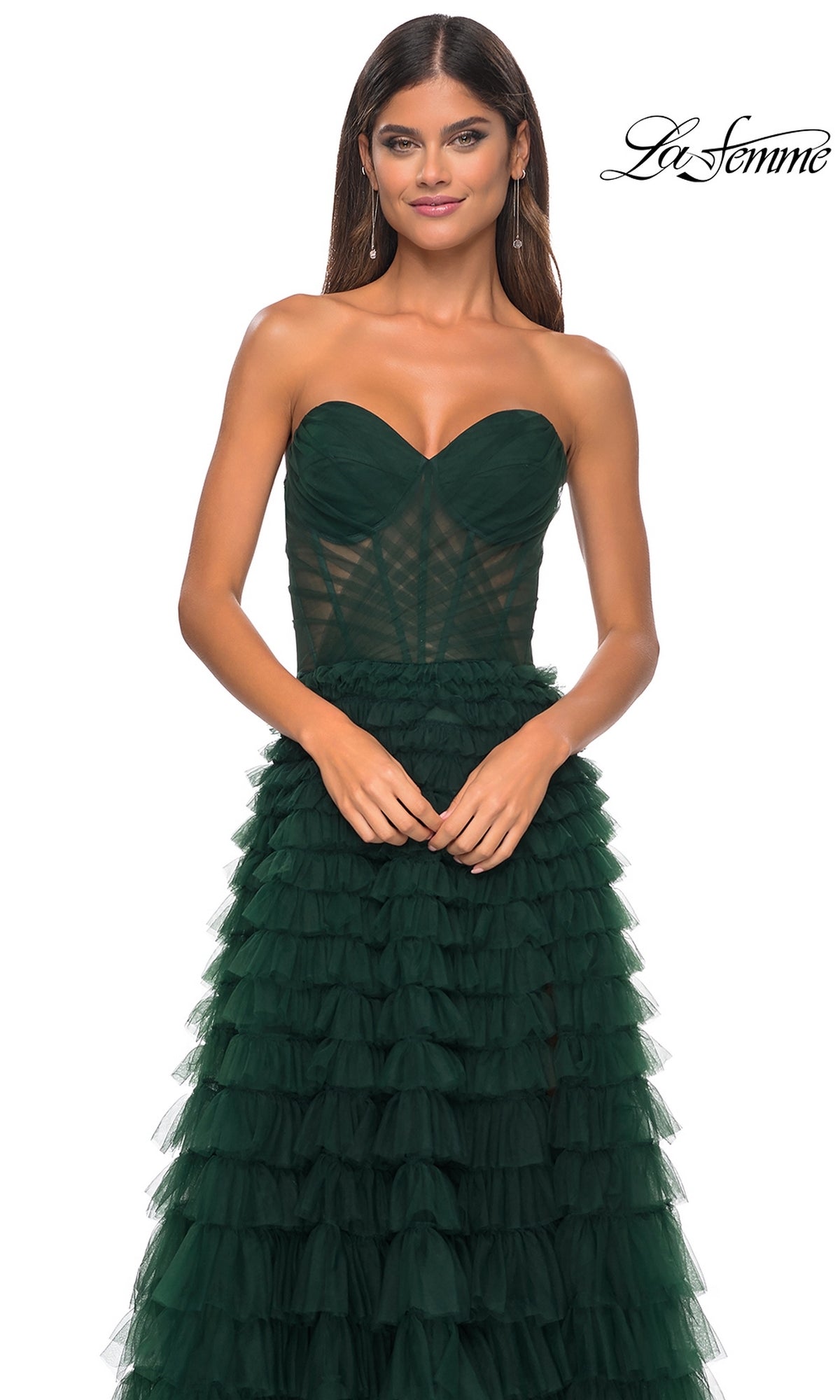A woman models the La Femme Strapless Long Ruffled Prom Dress 32283 in dark green tulle with a fitted bodice and ruffled A-line skirt, standing against a white background featuring the